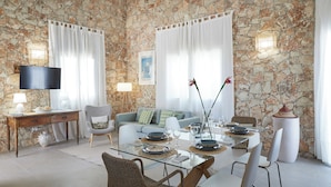 A dining area with a stone wall, a television, and a sofa. - Villa Zamia SicilyMyHome      (Ispica)