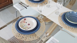A dining table set with blue and white plates, silverware, and clear wine glasses. - Villa Zamia SicilyMyHome      (Ispica)