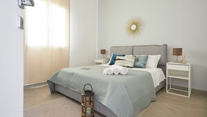 A neatly arranged bedroom with a bed, bedside tables, a nightstand, a decorative wall piece, and a patterned rug. - Villa Zamia SicilyMyHome      (Ispica)