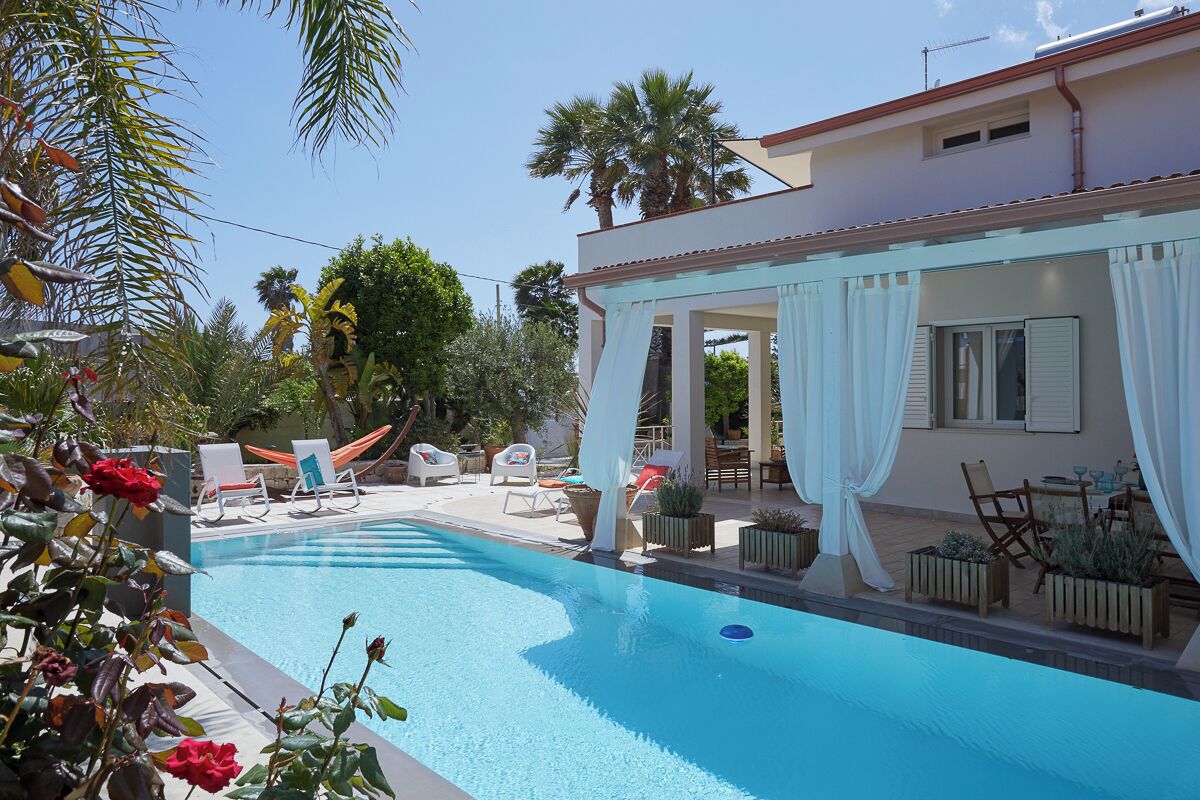 A swimming pool with lounge chairs and a covered patio area.