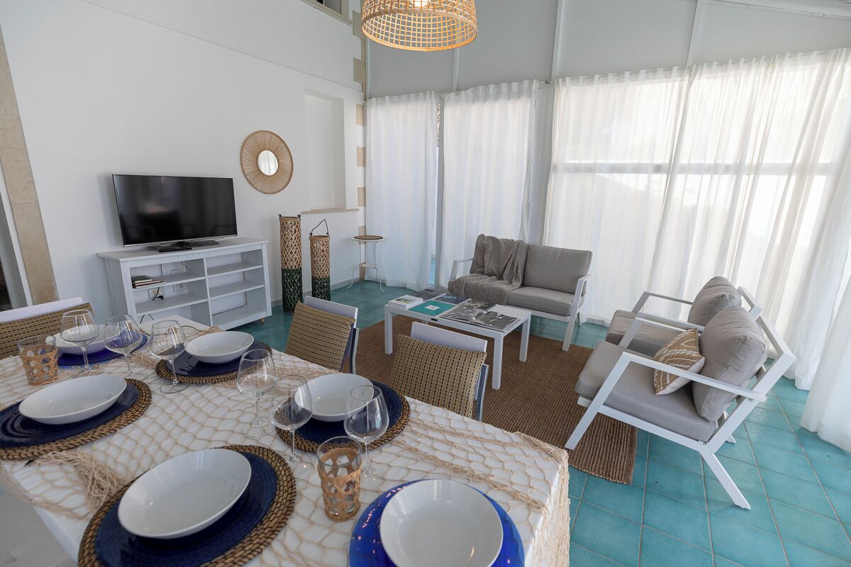 A modern living room with a TV, sofa, and dining area set for a meal.
