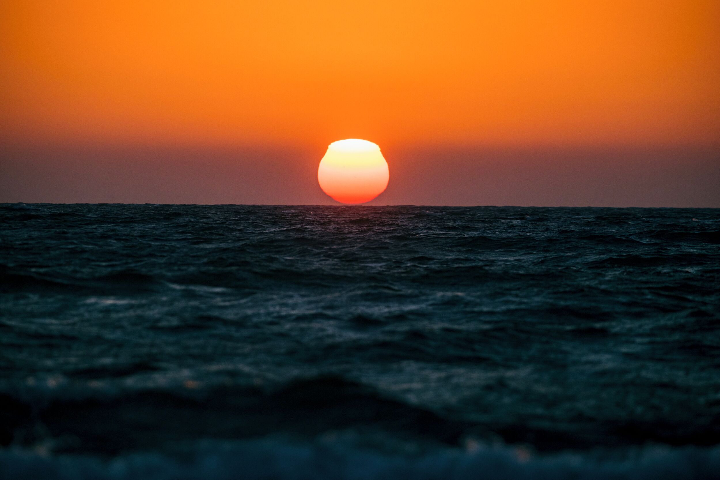 A sunset over the ocean with calm waters.