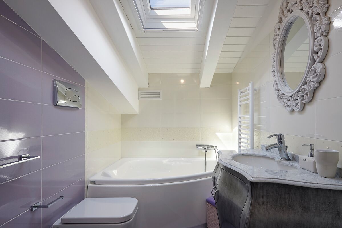 Un baño moderno con una bañera independiente, un tocador con espejo y un inodoro.
