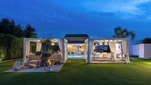 Un espace extérieur abrité comprenant une piscine, des sièges et une structure en forme de pergola.