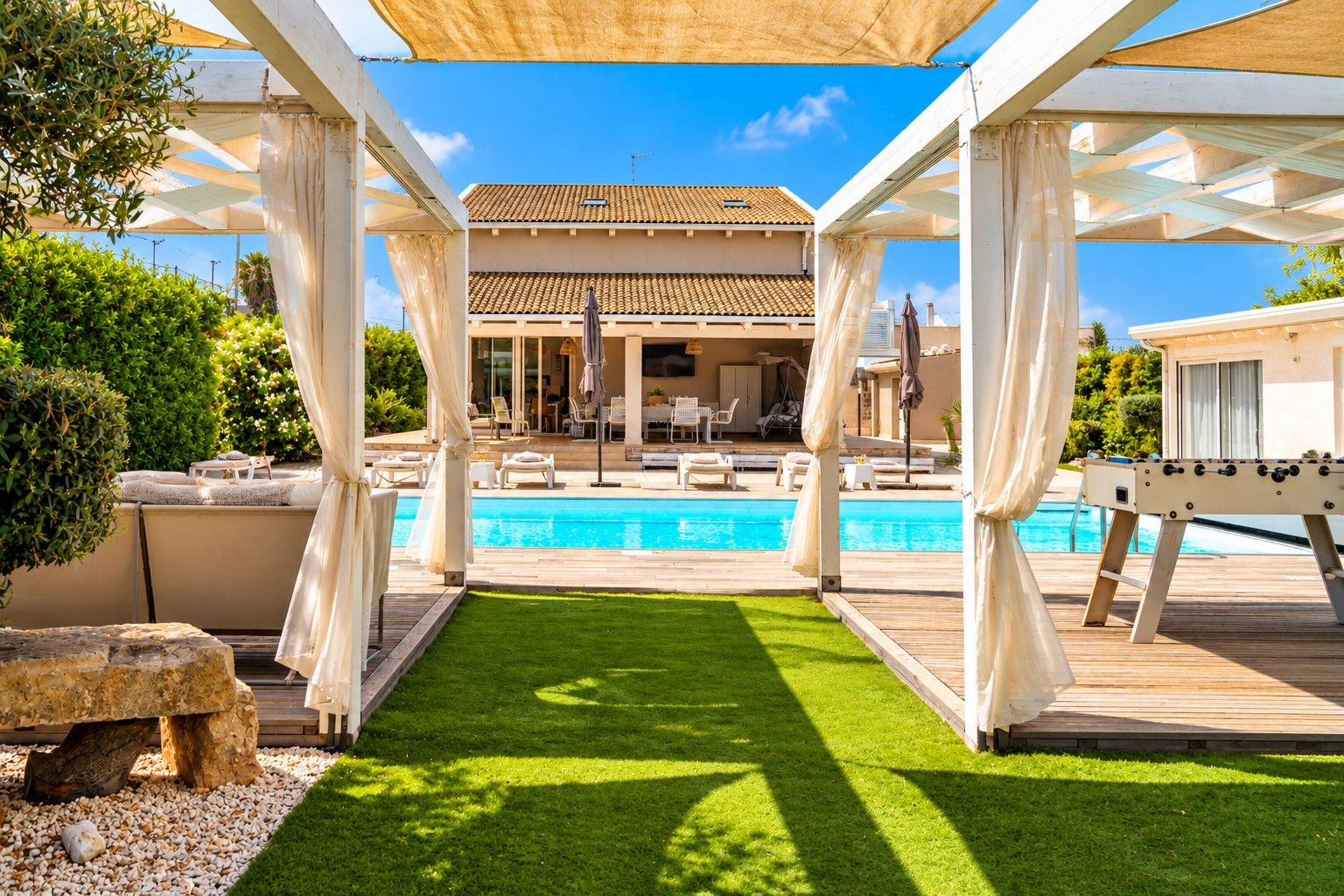 Zona de piscina con vista despejada, sillas de descanso y terraza de madera.