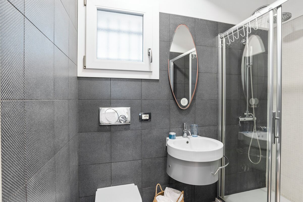 Een moderne badkamer met een douchecabine van glas, een wit wastafelmeubel en een grote spiegel.