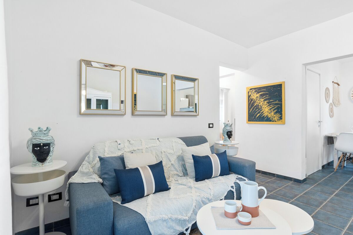 Una sala de estar moderna con un sofá azul, paredes blancas y una mesa de centro redonda.