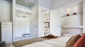 A modern bedroom with a bed, a wardrobe, a mirror, and a shelf with decorative items. - Villa Scarlet con Piscina Privata (Modica)