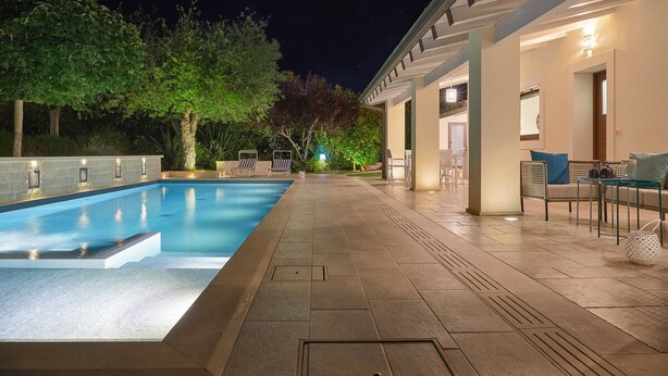 A swimming pool with a tiled deck, outdoor seating, and a night sky. - Villa Scarlet con Piscina Privata (Modica)