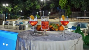 A table with three glasses of a red beverage, garnished with citrus slices, and a plate of fruits. - Villa del Colle con Piscina Privata (Ispica)