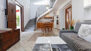 A spacious living area with a staircase leading to a kitchen, a dining table, and a sofa with decorative pillows. - Villa del Colle con Piscina Privata (Ispica)
