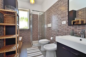 Un baño moderno con ducha, inodoro y lavabo, con salpicadero de azulejos y estantes de madera.
