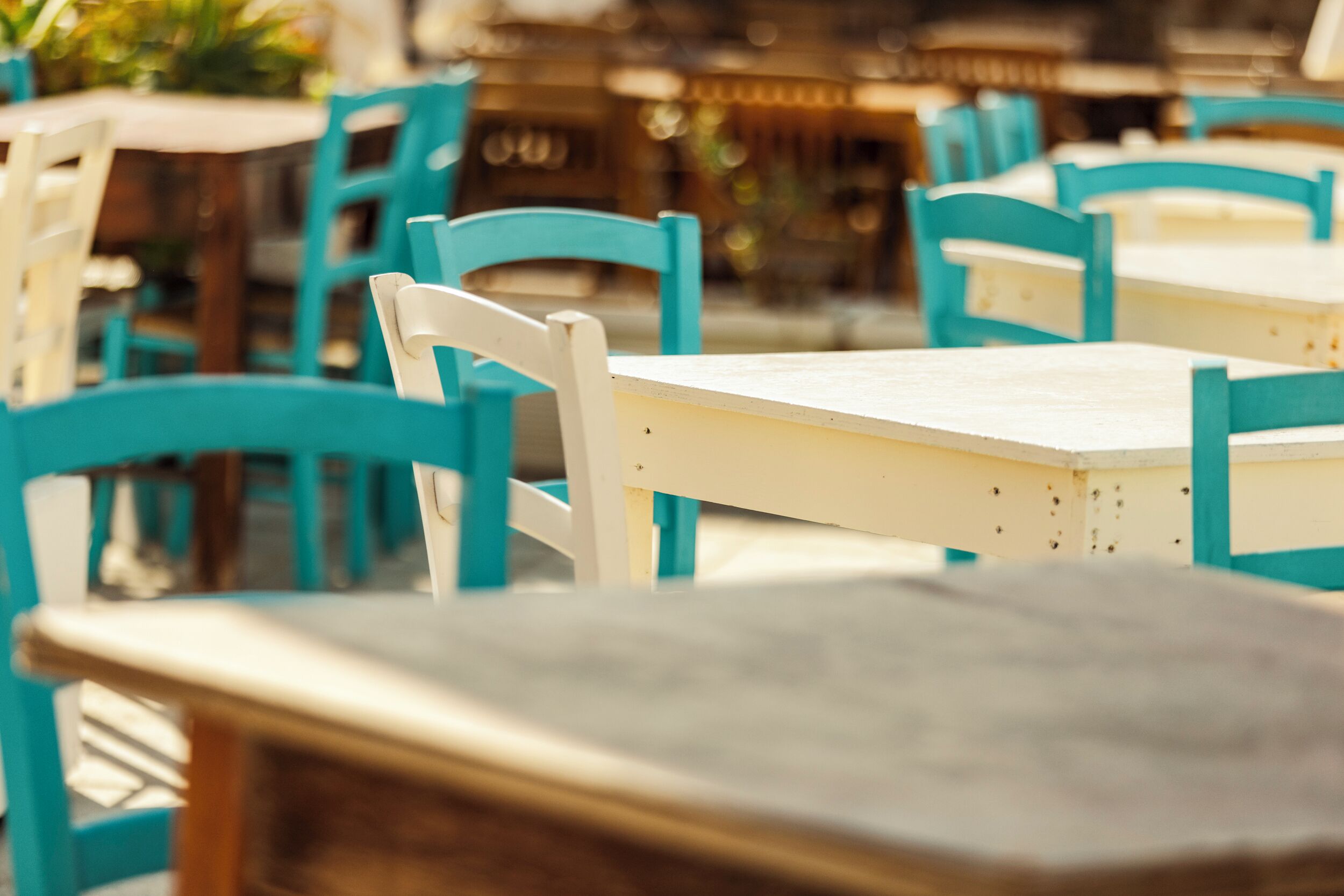 Een eetgedeelte met turquoise en witte stoelen en tafels, wat een informele sfeer suggereert.
