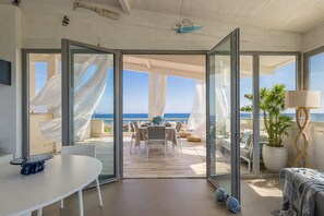 Ein Zimmer mit Glastür und Zugang zu einer Außenbereich-Sitzgelegenheit mit Meerblick.