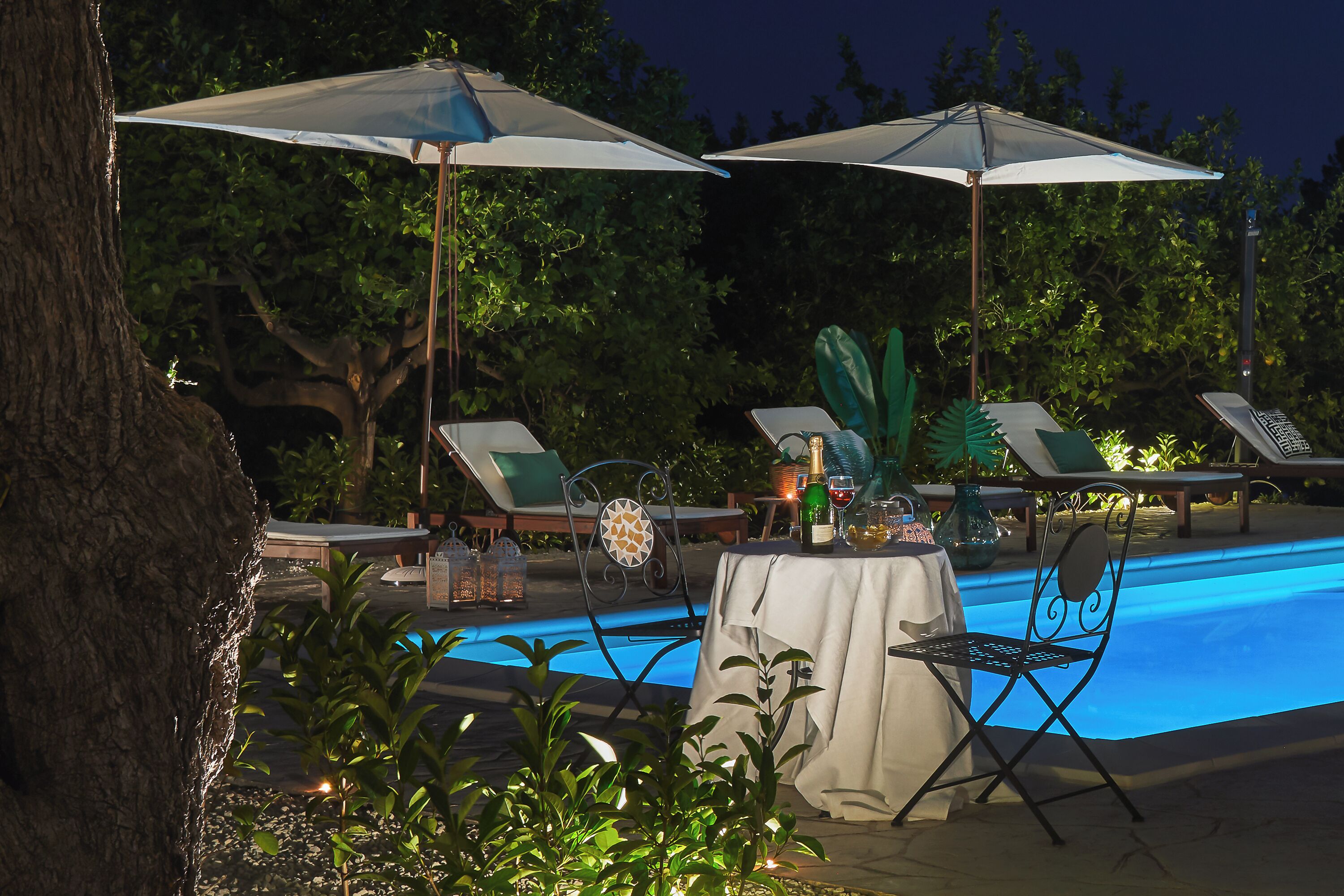 Un espace aménagé au bord de la piscine, avec des chaises longues, des parasols et une table dressée pour les repas.