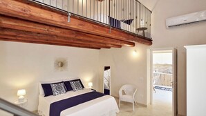 Une chambre à coucher comprenant un lit, une chaise, un miroir et un escalier menant à un niveau supérieur.