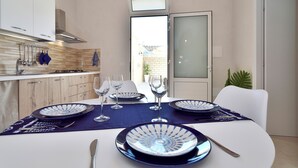 Une cuisine moderne avec des armoires blanches, une hotte en acier inoxydable et un coin repas agrémenté d’une vaisselle bleue et blanche, de verres et de couverts.
