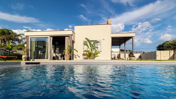 A modern house with a swimming pool, featuring a glass door entrance, a covered patio, and a small garden area. - Villa Olive & Champagne con Piscina Privata (Ispica)