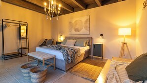 A bedroom with a bed, bedside tables, a chandelier, a standing lamp, and a wall-mounted artwork. - Villa Olive & Champagne con Piscina Privata (Ispica)
