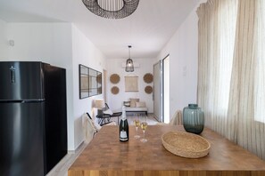 A modern kitchen with a black refrigerator, wooden dining table, and a woven basket. - Villa Olive & Champagne con Piscina Privata (Ispica)