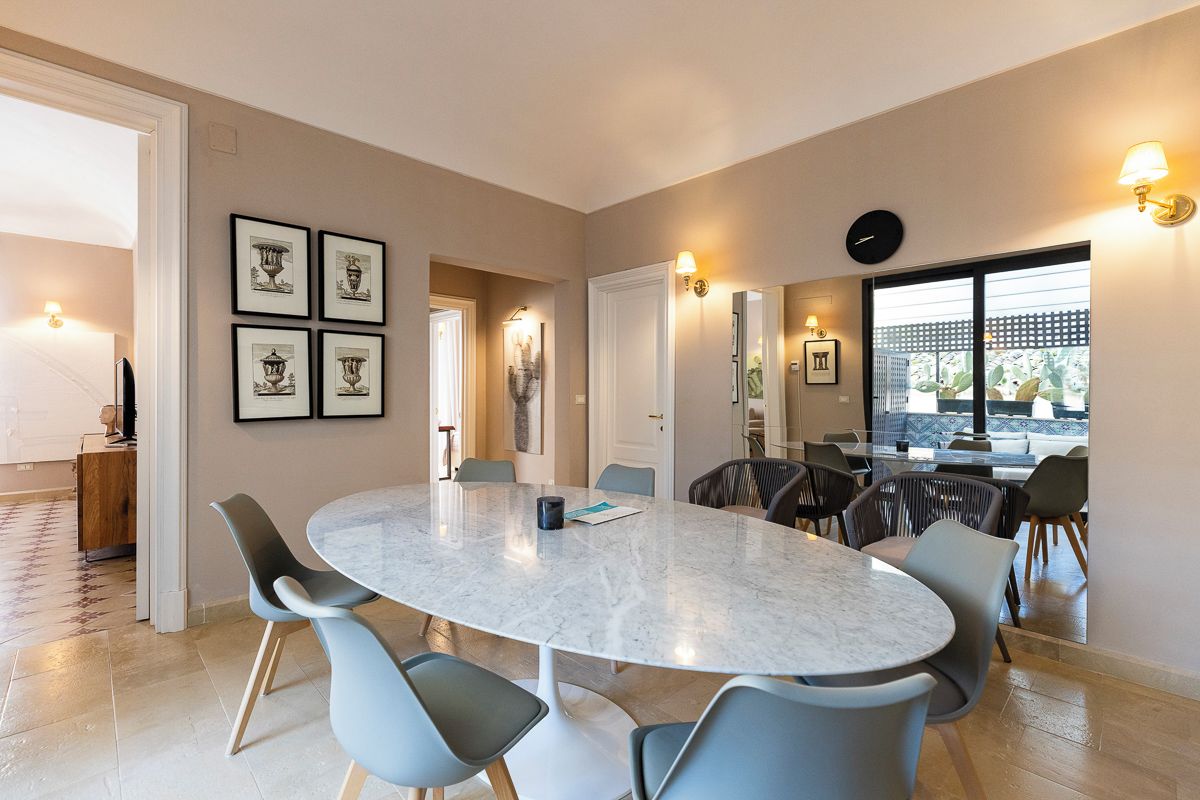 Un comedor moderno con una mesa de mármol, sillas azul claro y obras enmarcadas en las paredes.