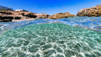 Agua cristalina, costa rocosa y edificios blancos.