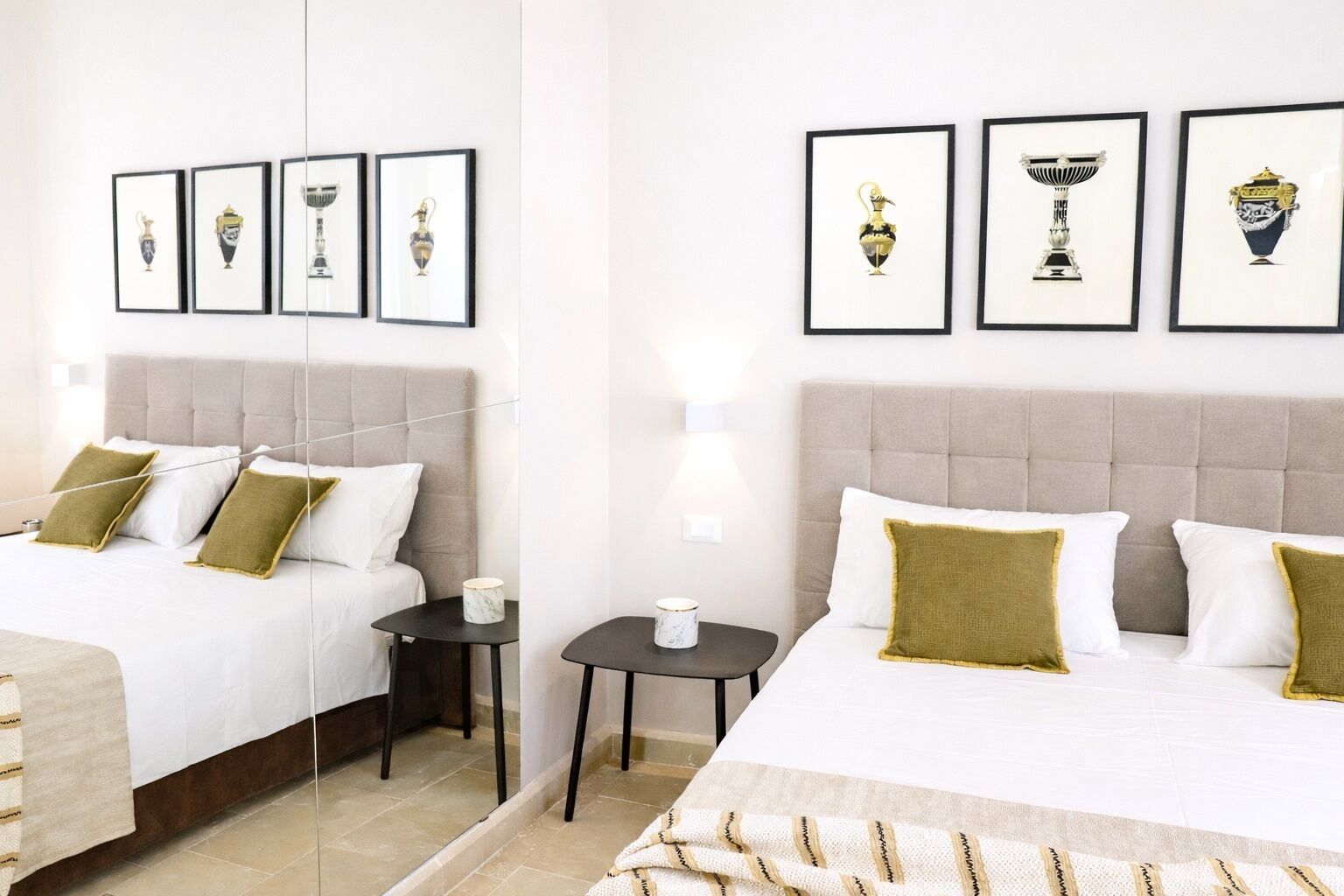 Una habitación de hotel con dos camas, una mesita de noche y cuadros en la pared.