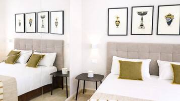 Una habitación de hotel con dos camas, una mesita de noche y cuadros en la pared.