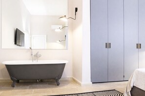 Une salle de bain moderne avec une baignoire sur pieds, un grand miroir et une armoire avec une porte coulissante.