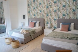 A modern bedroom with two beds, a nightstand, a lamp, and a woven basket. - Gemma di Mare SicilyMyHome (Pozzallo)