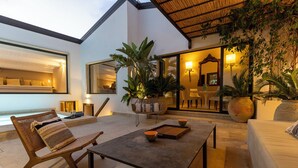 Un amplio espacio al aire libre con mesa de comedor, asientos y plantas en macetas.