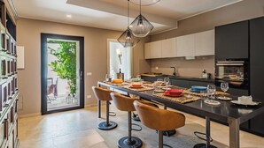 Una cocina moderna con comedor, que incluye una isla grande con taburetes de bar, una lámpara colgante y vistas al exterior.