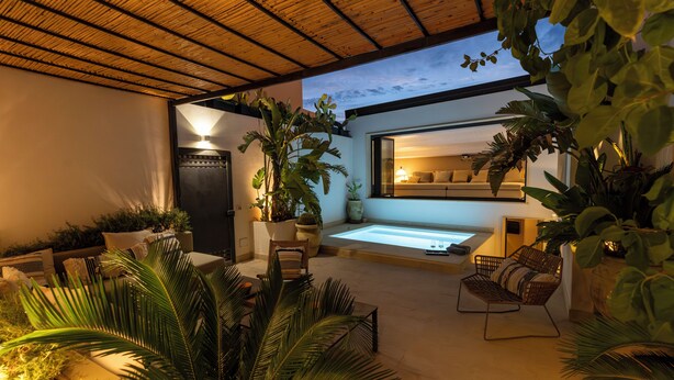 Un área exterior moderna con piscina, asientos y abundante vegetación.