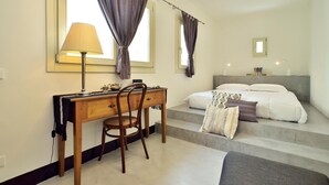 A bedroom with a bed, a desk with a chair, a lamp, and a window with curtains. - Domus Sbirciò Modica (Modica)