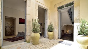 A courtyard with stone flooring, large potted plants, and a staircase leading to an upper level. - Domus Sbirciò Modica (Modica)