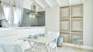 Eine moderne Küche mit weißen Schränken, einer gefliesten Spritzschutzwand und einem Essbereich mit weißem Tisch und Stühlen.