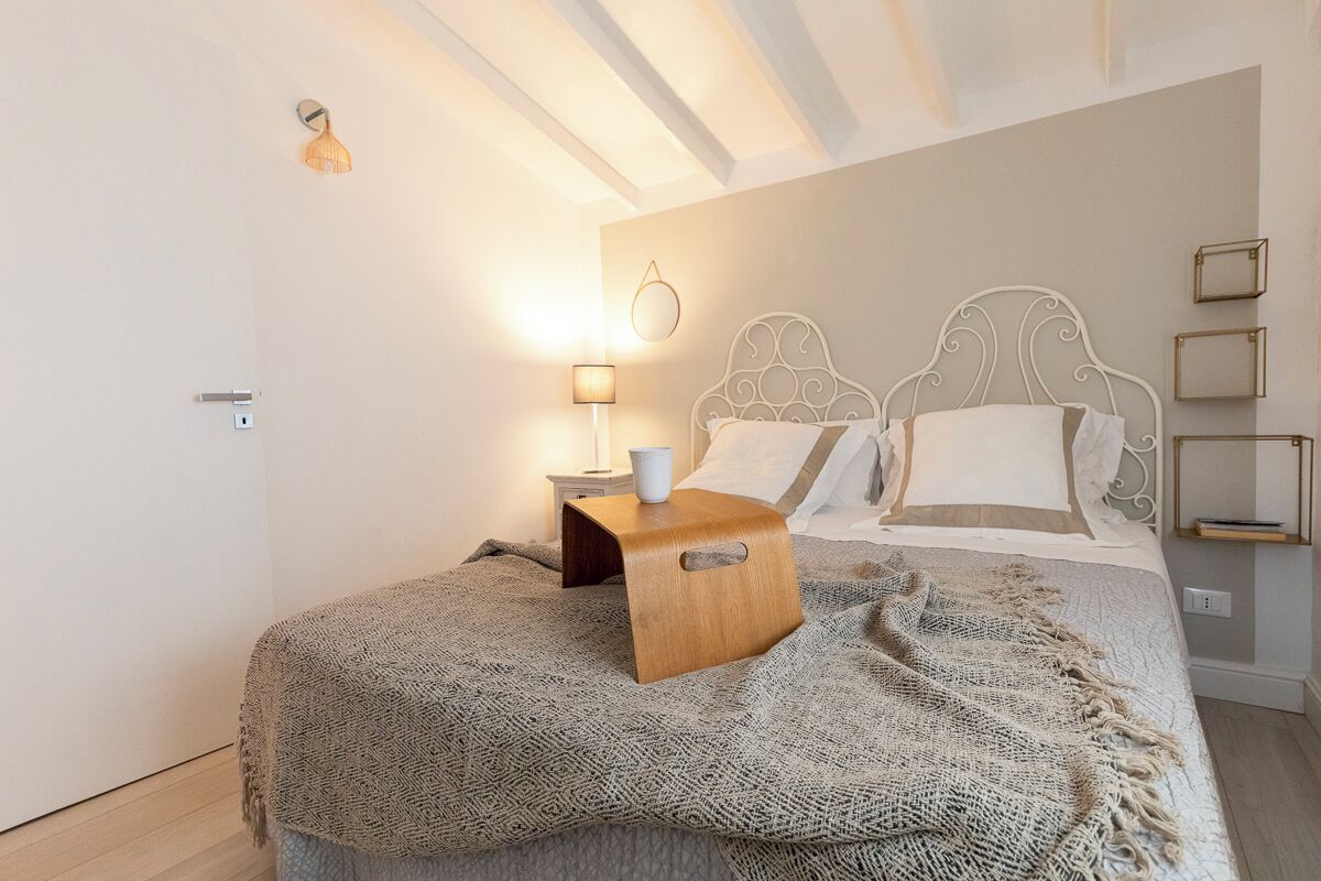 Ein Schlafzimmer mit Bett, Nachttisch, Lampe und Wandregalen.
