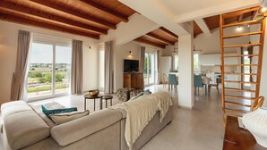 A spacious living area with a large sofa, a wooden ladder, and a view of the outdoors. - Villa Calicanto con Jacuzzi Riscaldata (Modica)