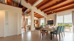 A spacious living area with a dining table, chairs, a TV, and a balcony with a view. - Villa Calicanto con Jacuzzi Riscaldata (Modica)