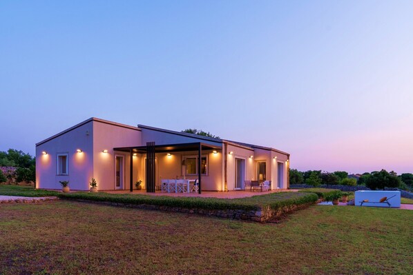 A modern two-story house with a covered patio, outdoor seating, and a well-maintained lawn. - Villa Calicanto con Jacuzzi Riscaldata (Modica)