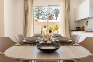 A dining table set with plates, bowls, and glasses, with a view of a balcony and trees outside. - Villa Aman Piscina e Jacuzzi Riscaldata (Ispica)