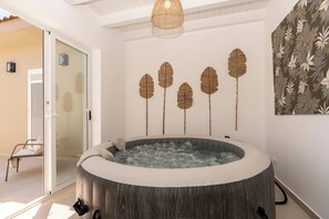 A spa room with a hot tub, a glass door leading outside, and a wall with leaf-shaped decorations. - Villa Aman Piscina e Jacuzzi Riscaldata (Ispica)