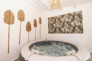 A spa room with a hot tub, wall-mounted wooden leaf decorations, and a floral-patterned painting. - Villa Aman Piscina e Jacuzzi Riscaldata (Ispica)