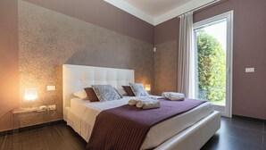 Una habitación de hotel moderna con una cama grande, una mesita de noche y una ventana con vistas a zonas verdes.