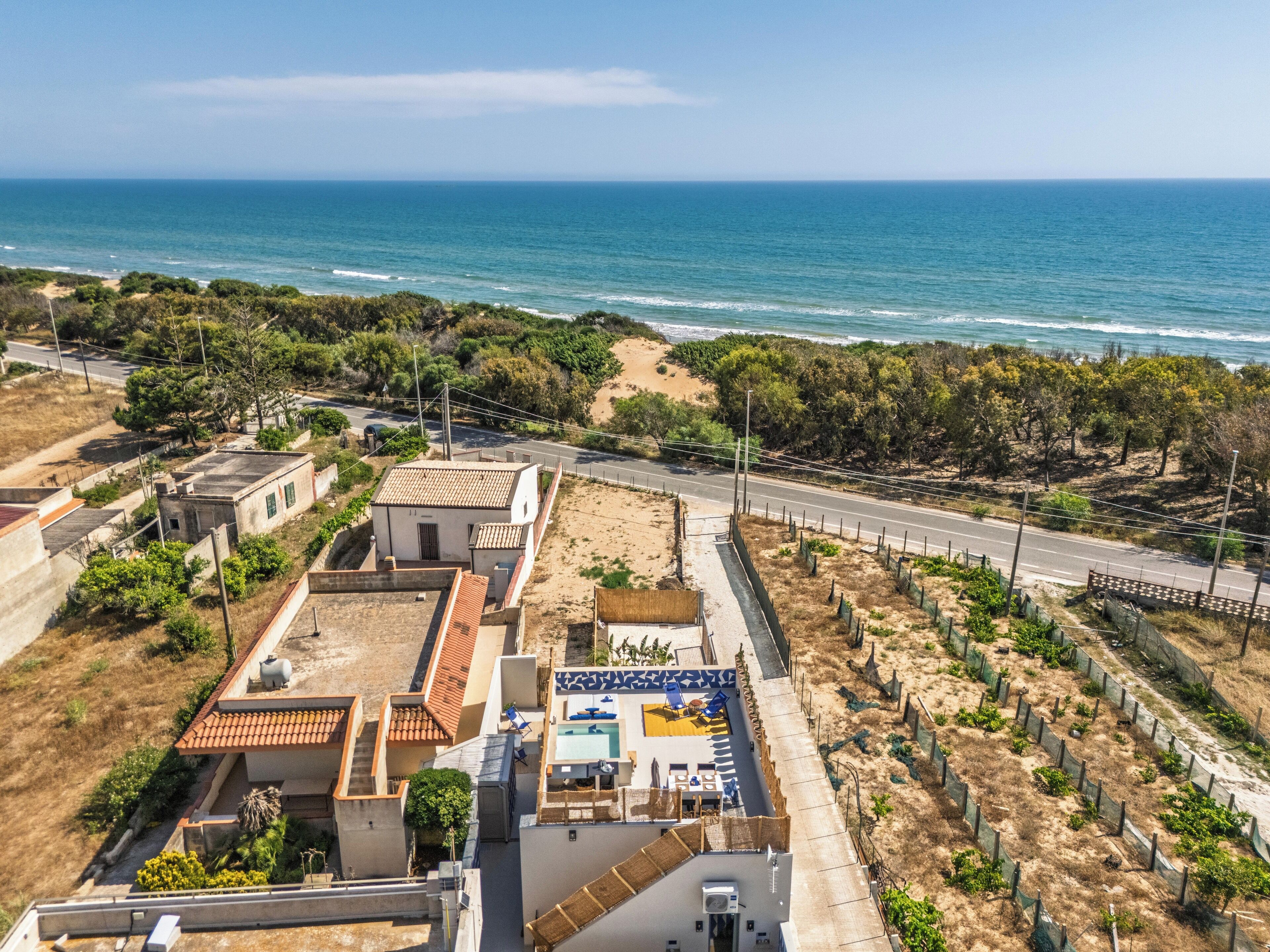 A coastal property with a swimming pool, a road, and a view of the sea.