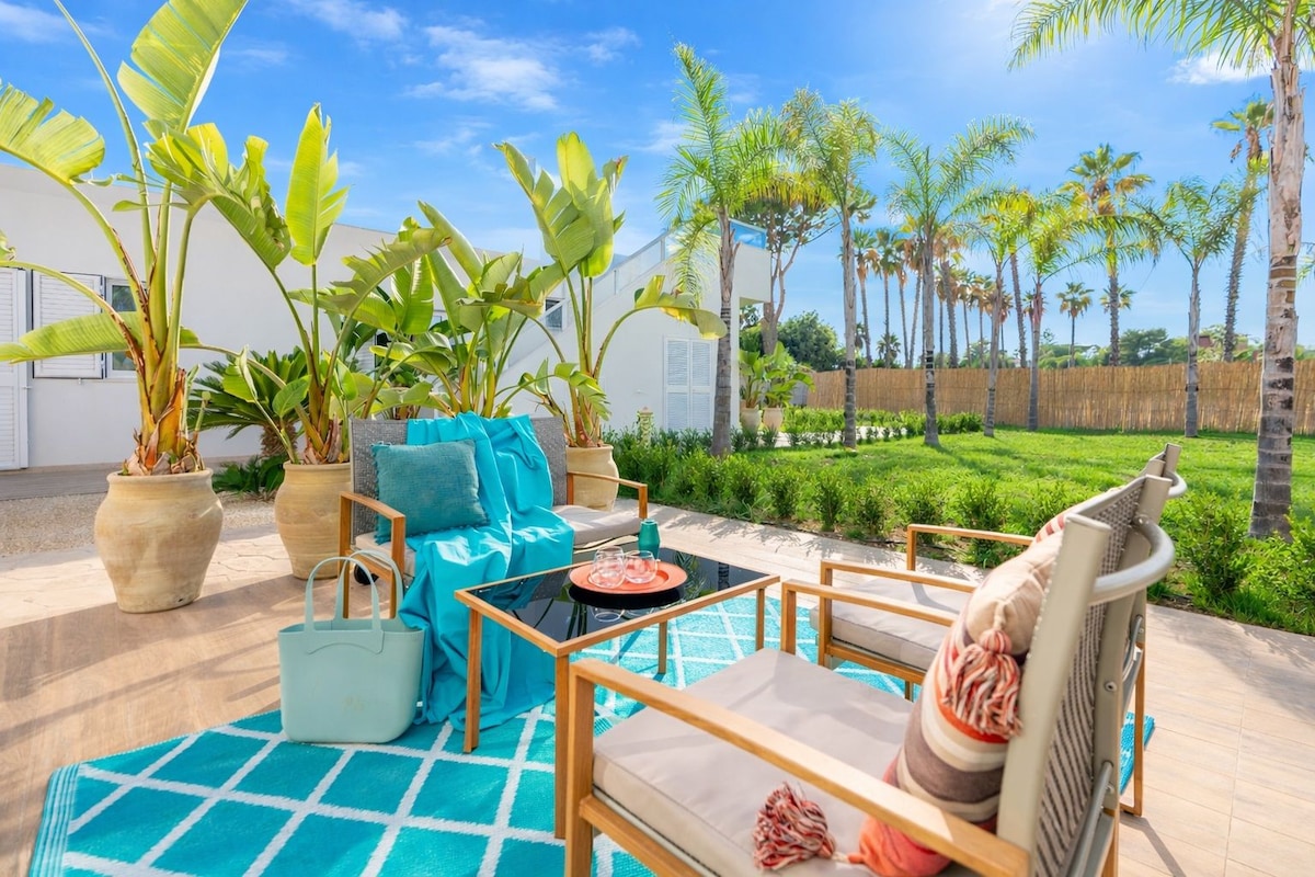 Un patio con mobiliario exterior, plantas en macetas y una piscina.