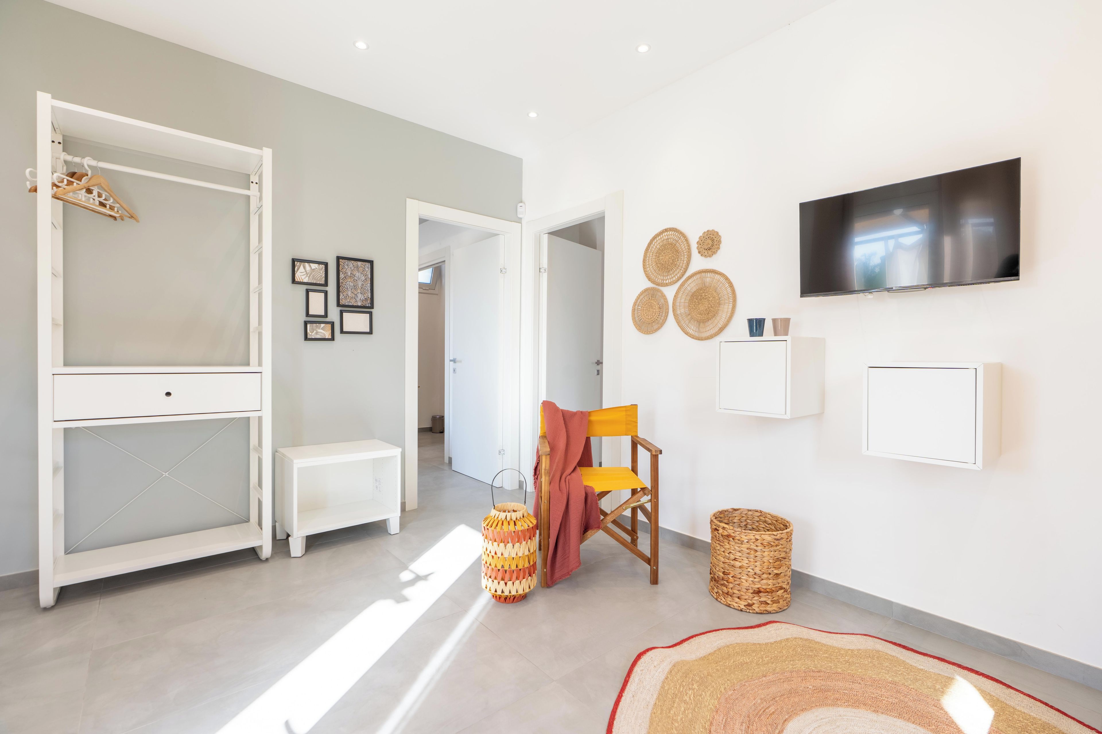A modern living room with a white console table, a bench, a TV mounted on the wall, and a woven basket on the floor.