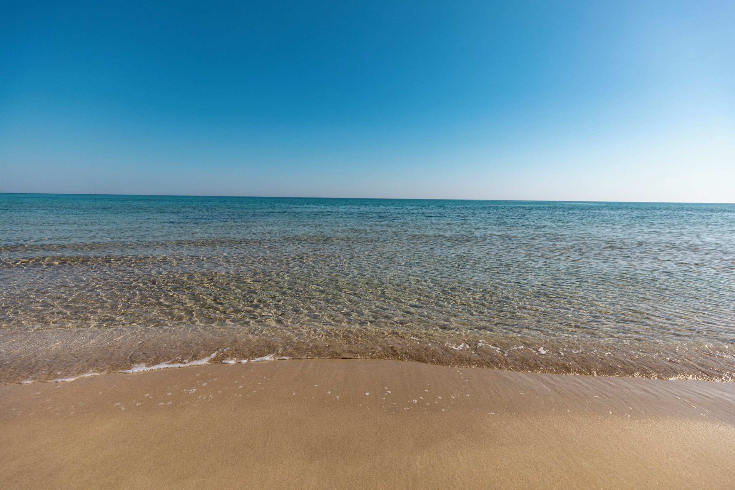 Una spiaggia con acque cristalline e una battigia sabbiosa.