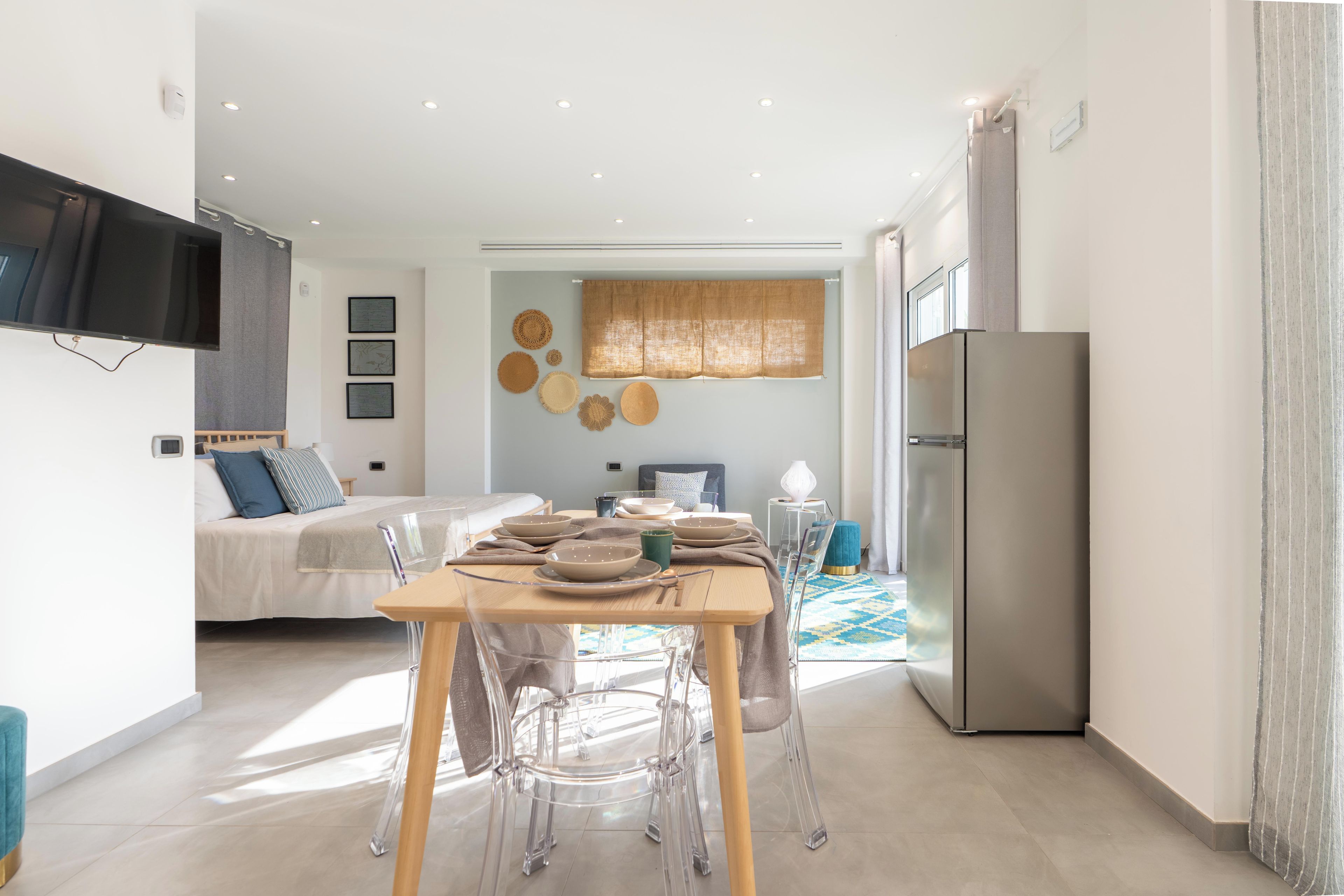 A modern living space with a dining area, a kitchen, and a bedroom.