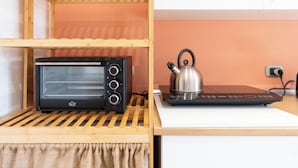 Una cocina compacta con horno tostador y hervidor sobre una encimera blanca.